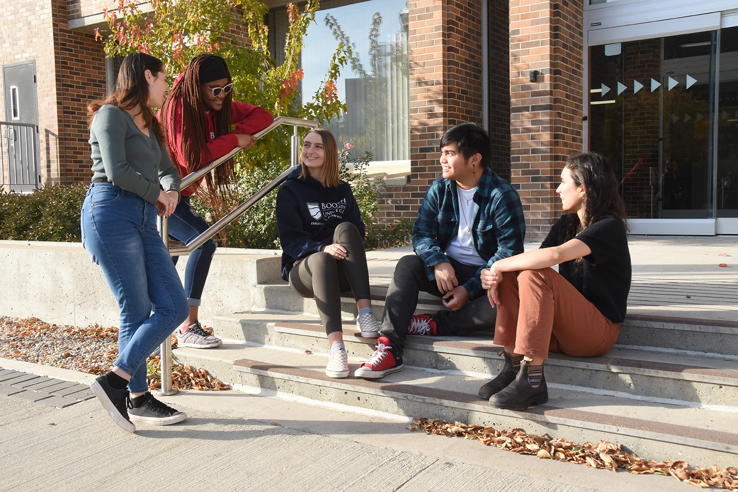 Students sitting on the steps outside the main campus building.