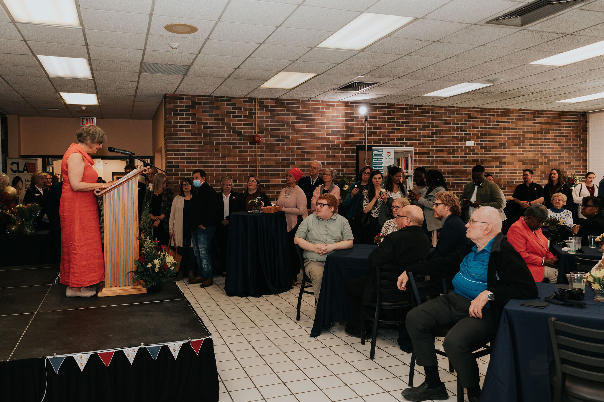 A woman is speaking at a podium on a stage at a special event.