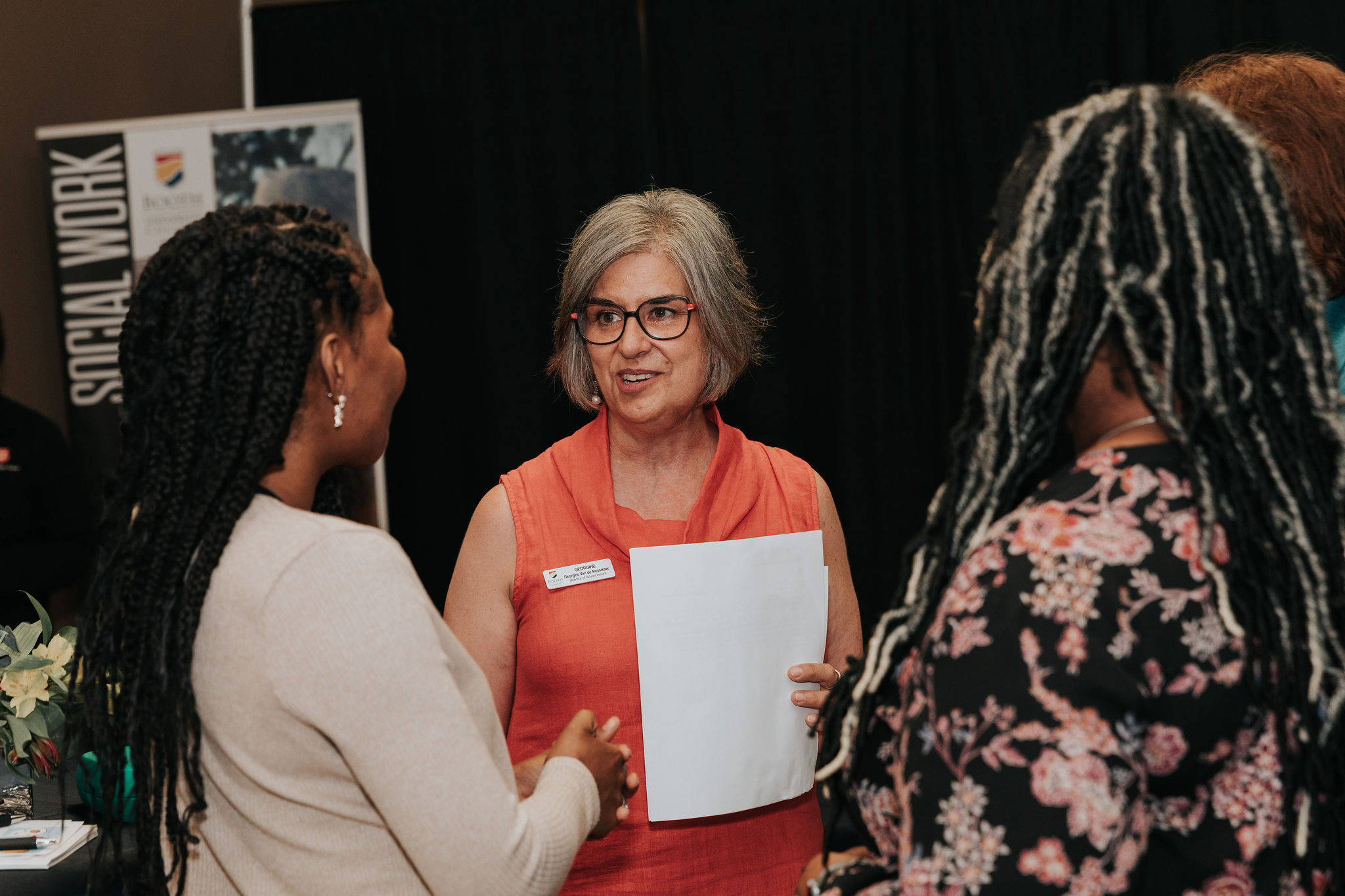 Three women talking at an event.