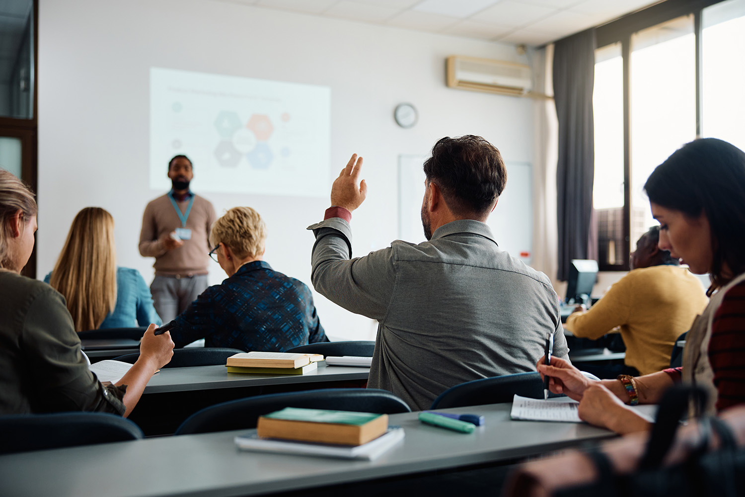 Student with his hand raised in class.