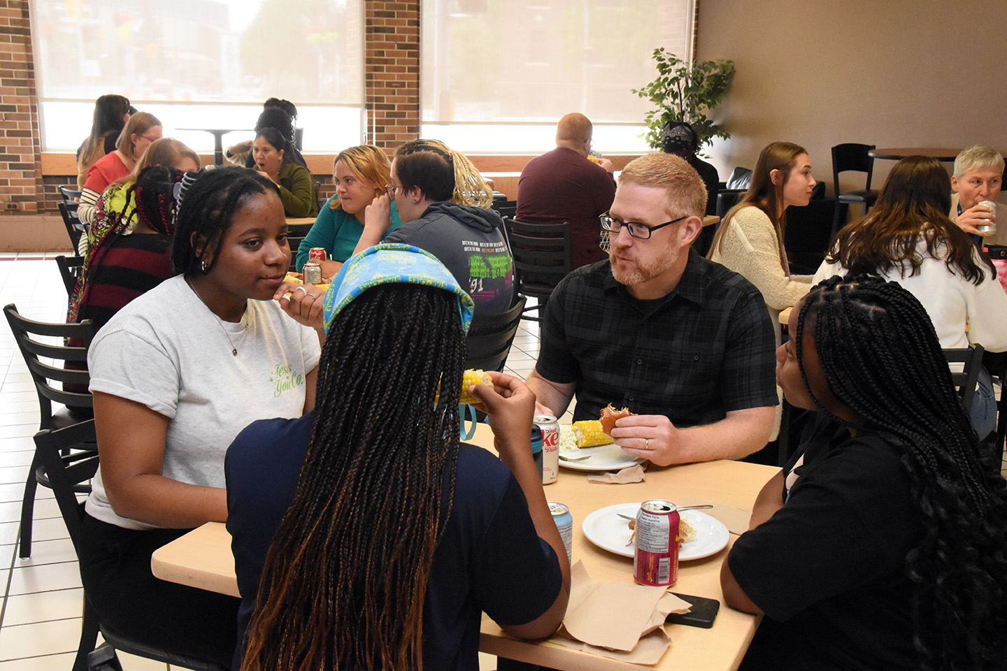 Students and instructors eating lunch and talking at tables of four in the Bistro.