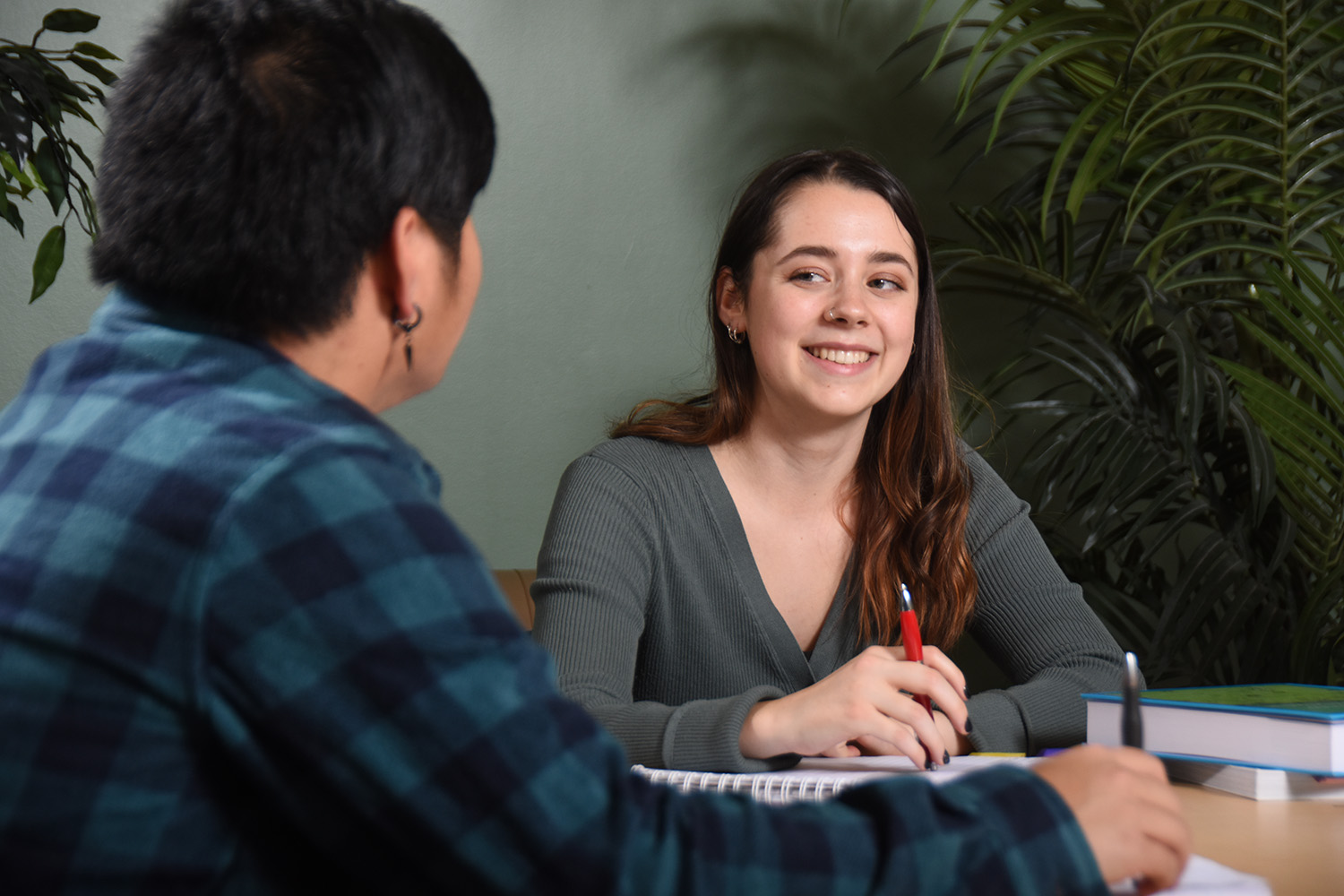 Two students sit across from each other at a desk.