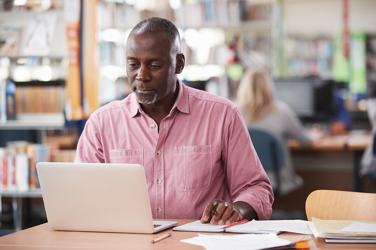 Middle-aged man sitting at a computer in a classroom.